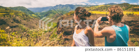 Couple tourists taking phone pictures of Hawaii nature landscape with smartphone camera app. Travel lifestyle people enjoying summer vacation 86151891
