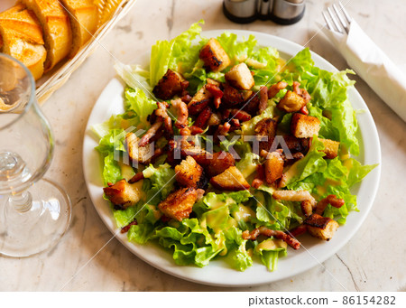 Lettuce, crouton, lardon salad on plate Lettuce, crouton, lardon salad on plate 86154282