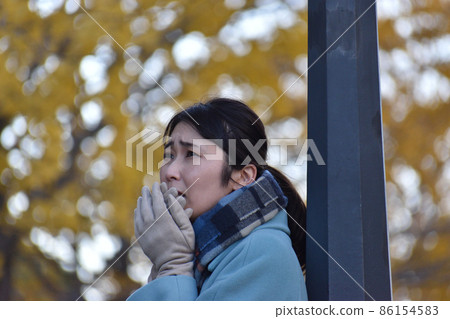A young woman in a coat worried on the street 86154583