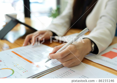 Close-up, businesswoman holding a pen, taking notes on report. 86155146