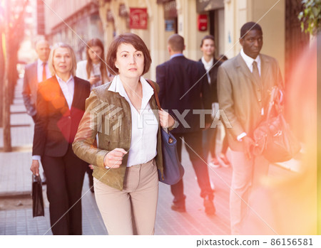 Portrait of hurrying woman among passers 86156581