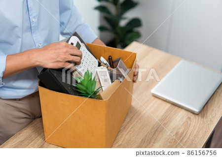 Resignation Concept The man in light blue shirt standing at the desk and putting the calculator and other stuff into the box 86156756