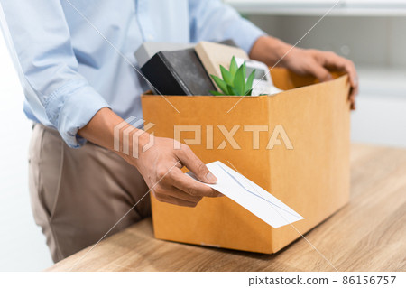 Resignation Concept The male officer standing, putting his box of his belongs on the desk and handing the white letter to someone 86156757