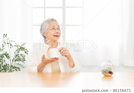 Elderly woman drinking a drink in a mug 86156871