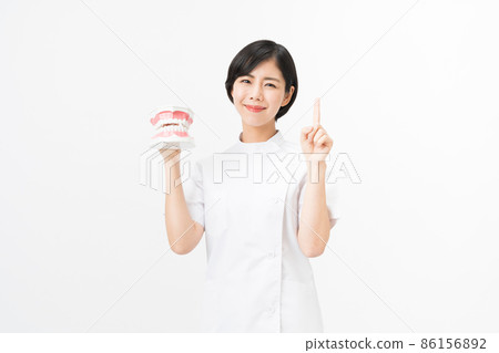 Young female dental hygienist with a tooth model (white background) Young female dental hygienist with a tooth model (white background) 86156892