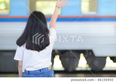 A young woman waved goodbye to her friend on a running train. 86156950