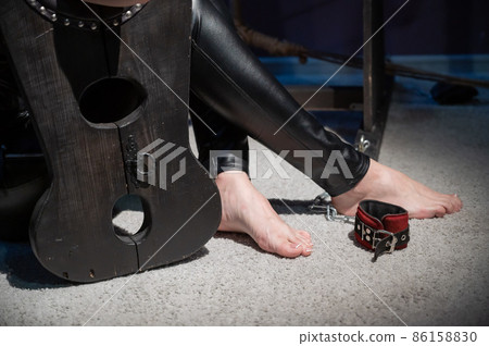 Female hands in wooden shackles during role-playing games. Shameful pillar and leather cuffs for sex. BDSM Domination and punishment. 86158830