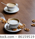 2 cups of coffee latte in a cafe on a wooden table with pretzels 86159519