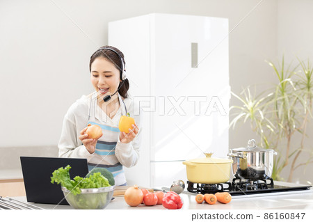 家庭時間:一位年輕女性一邊使用電腦一邊做飯 家庭時間:一位年輕女性一邊使用電腦一邊做飯 86160847