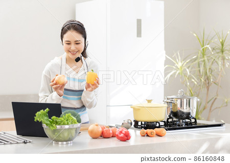 家庭時間:一位年輕女性一邊使用電腦一邊做飯 家庭時間:一位年輕女性一邊使用電腦一邊做飯 86160848
