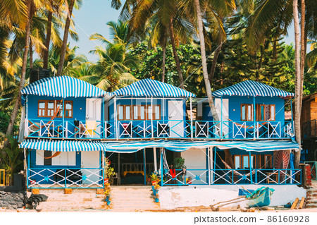 Canacona, Goa, India. Famous Painted Guest Houses On Beach Against Background Of Tall Palm Trees In Sunny Day 86160928