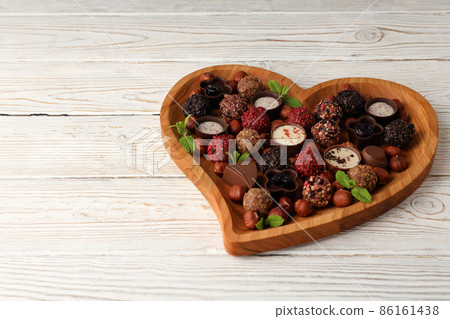 Concept of sweets with chocolate candies on white wooden background Concept of sweets with chocolate candies on white wooden background 86161438