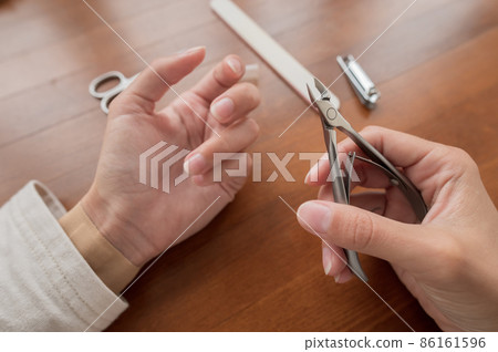 Caucasian girl makes herself a manicure at home. Close-up young woman uses nail clippers 86161596