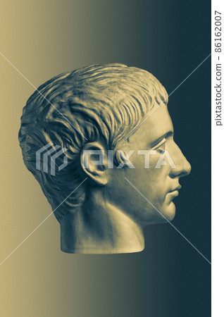 Bronze color gypsum copy of ancient statue of Germanicus Julius Caesar head for artists on brass background. Renaissance epoch. Plaster sculpture of man face. Template for art design 86162007