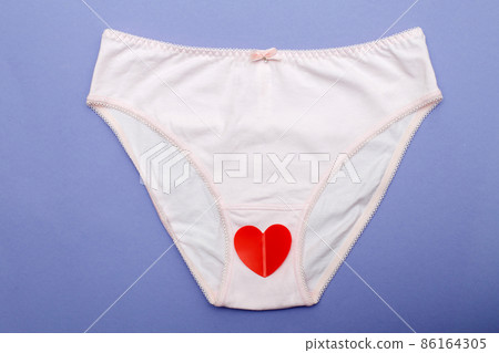 pink women's briefs with a heart on a purple background. hygiene and women's health care concept pink women's briefs with a heart on a purple background. hygiene and women's health care concept 86164305
