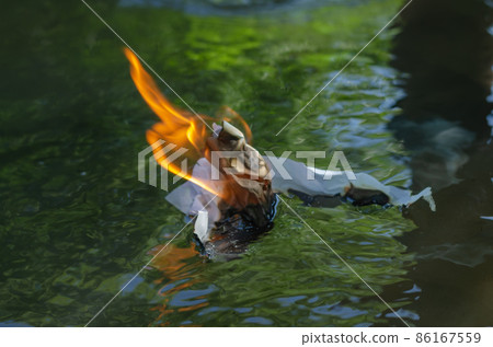 A flaming piece of white paper floats down the river 86167559