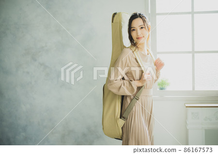 Female with a guitar case Female with a guitar case 86167573