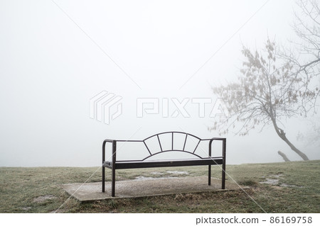 An empty bench on the shore of a misty autumn lake. Loneliness concept. 86169758