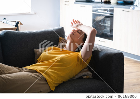 Young millenial woman lying on the couch tired with headache. 86169806