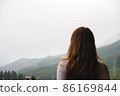 Young redhead woman admires mountains in autumn, back view. 86169844