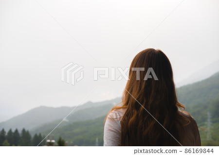 Young redhead woman admires mountains in autumn, back view. 86169844