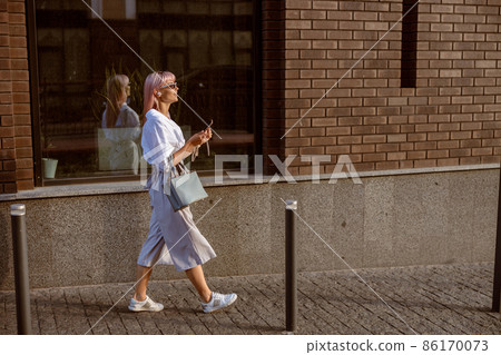 Young woman walking on the street and listening to music Young woman walking on the street and listening to music 86170073