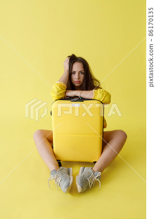 Cute young woman with travel bag sitting in studio Cute young woman with travel bag sitting in studio 86170135