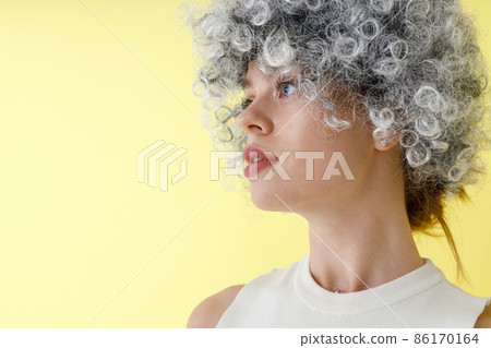 Pretty young woman in wig standing in studio 86170164