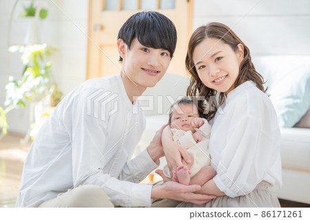 Portrait of mom, dad and three babies sitting and smiling in the living room Portrait of mom, dad and three babies sitting and smiling in the living room 86171261