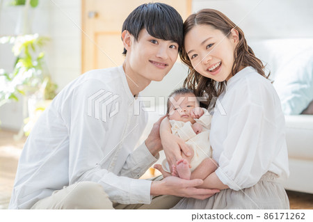 Portrait of mom, dad and three babies sitting and smiling in the living room Portrait of mom, dad and three babies sitting and smiling in the living room 86171262