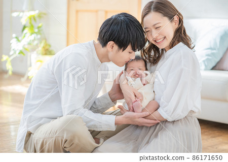 Portrait of a young dad kissing a baby and a smiling mom 86171650