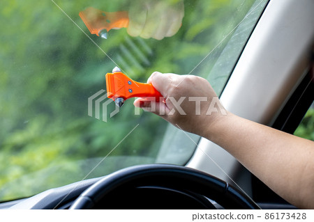 Woman use Safety Hammer and Seatbelt Cutter in Cars, break glass When emergency. 86173428
