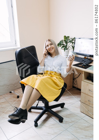 SMM specialist, Social Media Expert, Remote Social Media Pro. Young girl SMM manager with a phone at the workplace near computer with open social media page website SMM specialist, Social Media Expert, Remote Social Media Pro. Young girl SMM manager with a phone at the workplace near computer with open social media page website 86174802