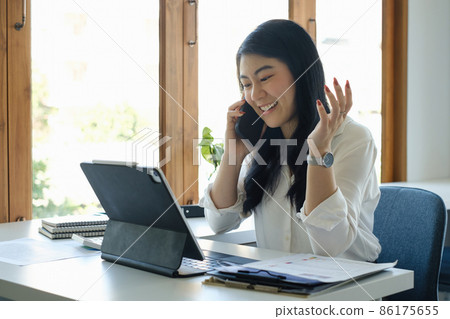 Asian Businesswoman discussing with her team by mobile phone while relexing at coffee shop. Finance concept. Asian Businesswoman discussing with her team by mobile phone while relexing at coffee shop. Finance concept. 86175655