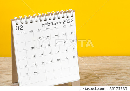 February 2022 desk calendar on wooden table with yellow background. February 2022 desk calendar on wooden table with yellow background. 86175785