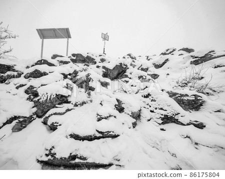Close up to rocky terrain with fresh powder snow, landscape hidden in heavy fog. Close up to rocky terrain with fresh powder snow, landscape hidden in heavy fog. 86175804
