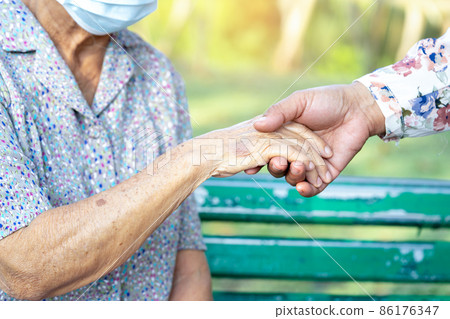 Caregiver daughter holding Touching hands Asian senior or elderly old lady woman patient with love, care, helping, encourage and empathy at nursing hospital ward, healthy strong medical concept. 86176347