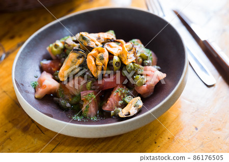 Tomatoes with arugula pesto and mussels served on a plate 86176505