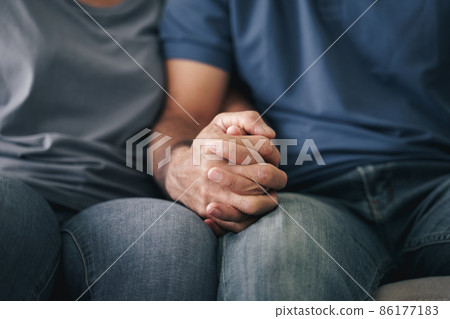 Close up of Asian mature couple sitting on the couch. wife and husband holding hand with happiness and cheerful. Love, safety, and insurance family concept. 86177183