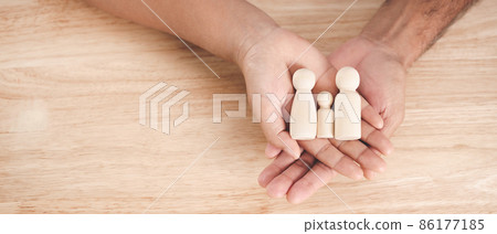 Man husband and Woman wife hands holding wooden peg dolls on the wood table background. family home, foster care, homeless charity support concept, family mental health.. 86177185
