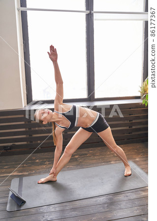 Young woman going yoga exercise at home. Health care online lessons. Indoor 86177367