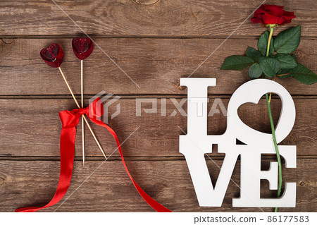Red rose and candy over wooden background 86177583