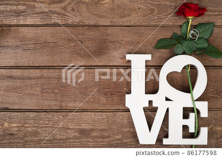 Red rose and ring over wooden background 86177598