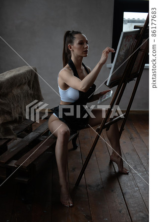 Alluring woman in apron drawing picture at easel 86177683