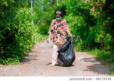 Senior woman picking up plastic bottle 86178346
