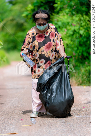 Senior woman picking up plastic bottle 86178347