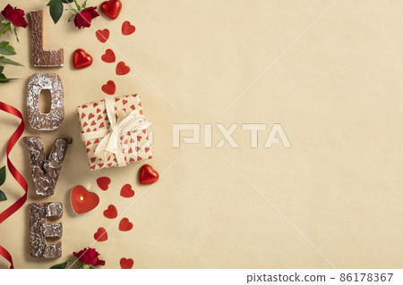 Valentine's day composition with gift box in craft recycling paper flowers, candles, chocolate and wooden letters, top view, space for text or logo 86178367