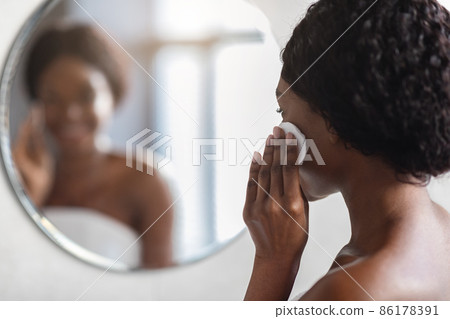 Blurred mirror reflection of woman removing makeup with cotton pads Blurred mirror reflection of woman removing makeup with cotton pads 86178391