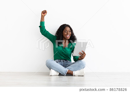 Happy black woman with digital tablet raising hand up 86178826