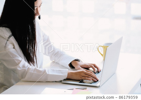 Young friendly operator woman agent with headsets working with laptop computer Young friendly operator woman agent with headsets working with laptop computer 86179359